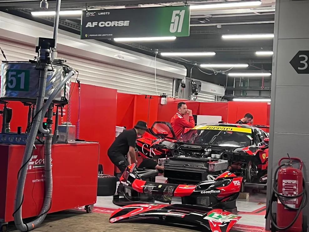 Des mécaniciens au travail sur une GT dans le box rouge de son team