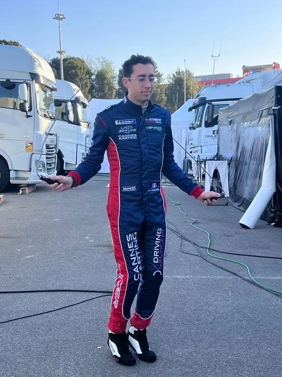 Un pilote en combinaison s'active dans le paddock avant de monter en voiture